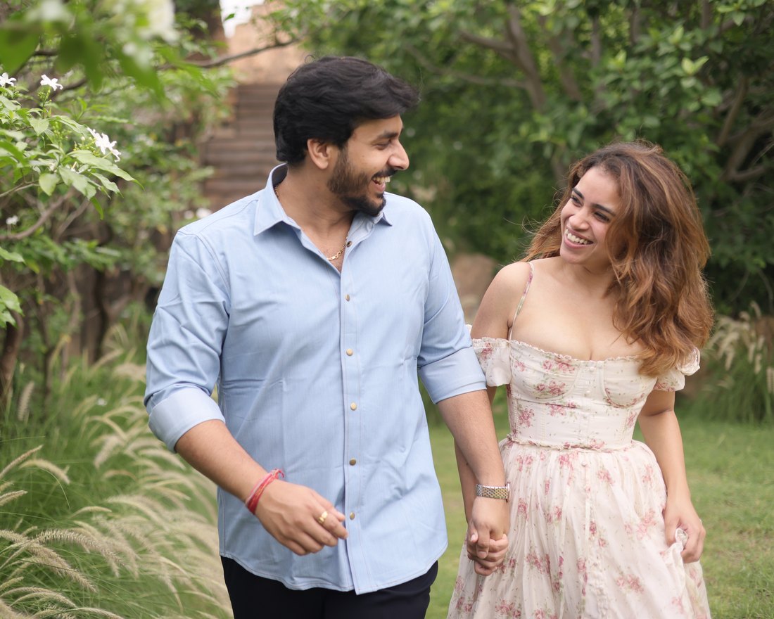 Anukriti and Anuj walking hand in hand through a garden, laughing